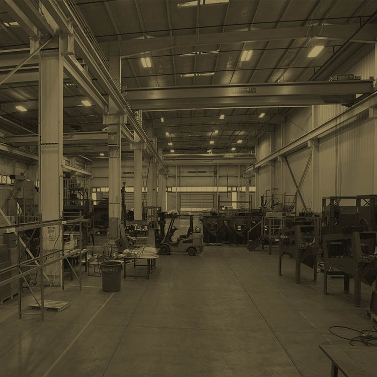 Interior of a facility where workers are driving forklifts and working on large electrical engines.